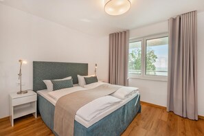 Ein modernes Schlafzimmer mit einem Bett, Nachttischen und einem Fenster mit Vorhängen.