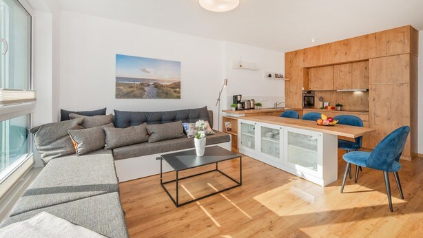 Una sala de estar moderna con un sofá, una mesa de centro y vista a la cocina.