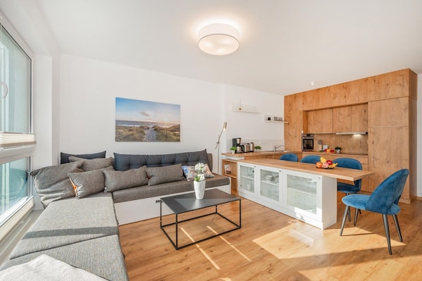 A modern living room with a sofa, coffee table, and a view of the kitchen.
