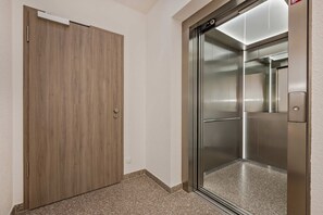 A hallway with a wooden door and a modern elevator. - Ferienwohnung Terrasse am Haff - Hochwertig Eingerichtetes Ferienappartment in Ruhiger Lage mit Wlan (Zirchow)