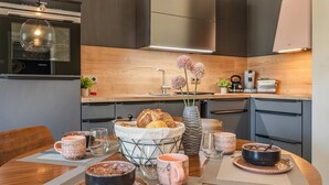A modern kitchen with a built-in oven, a stainless steel range hood, and a wooden countertop. - Ferienwohnung Terrasse am Haff - Hochwertig Eingerichtetes Ferienappartment in Ruhiger Lage mit Wlan (Zirchow)