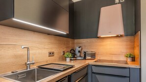 Une cuisine moderne dotée d’appareils électroménagers en acier inoxydable, de plans de travail en bois et d’un lave-vaisselle encastré.