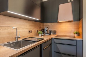 A modern kitchen with stainless steel appliances, wooden countertops, and a built-in dishwasher.