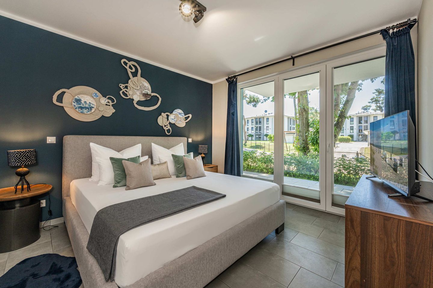 Een moderne slaapkamer met een groot bed, een flatscreen televisie en uitzicht op de omgeving.