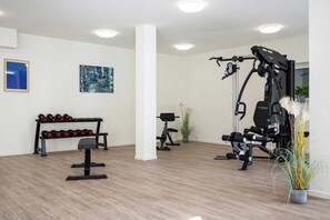 A gym with exercise equipment, dumbbells, and a plant. - Ferienwohnung Klippenblick (Garz)