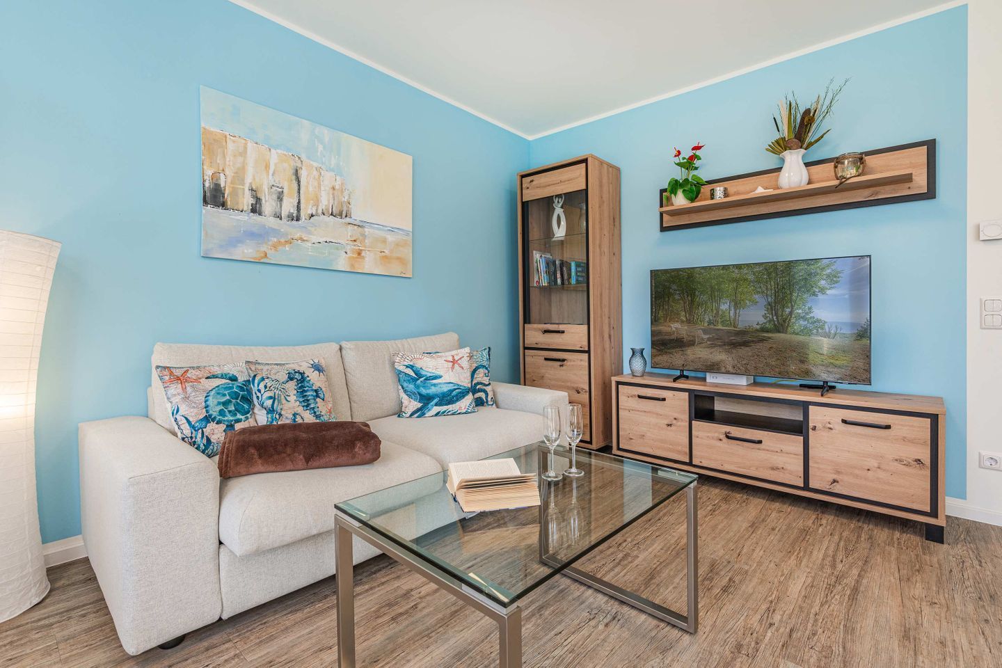 Una sala de estar moderna con un sofá, una mesa de centro, un televisor y una estantería.