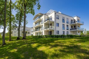 A multi-story residential building with balconies, surrounded by greenery and trees. - Ferienwohnung Klippenblick (Garz)