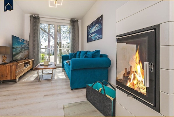 A living room with a sofa, a wooden coffee table, a fireplace, and a TV.