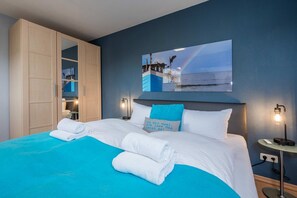 Une chambre d’hôtel avec un lit, un grand miroir, une table de chevet et un tableau accroché au mur.