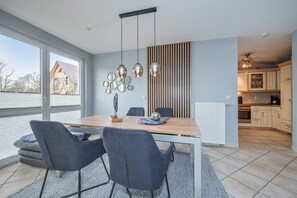 Ein stilvoller Essbereich mit Holztisch, grau gepolsterten Stühlen und Pendelleuchten.