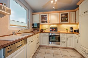 A modern kitchen with white cabinetry, a stainless steel oven, and a built-in microwave.
