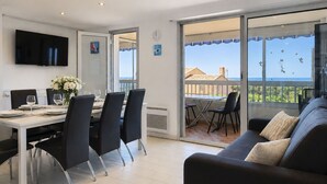 Un comedor con una mesa para cuatro, un sofá y un balcón con vistas.
