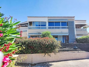 Un bâtiment à deux étages doté d’un balcon, d’une entrée couverte et d’un petit jardin.