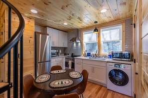 A compact kitchen with a refrigerator, oven, microwave, and washing machine.