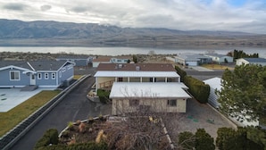 A residential area with houses, a driveway, and a lake with mountains in the background.