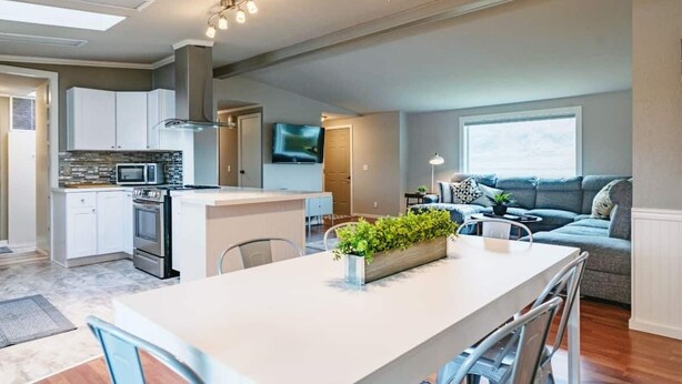 A modern kitchen with white cabinets, a central island, and a built-in microwave.