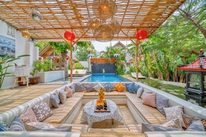 Relax in a serene outdoor space with cushioned benches, a decorative Buddha statue, and a shaded pergola.