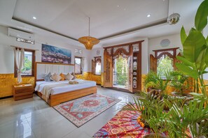 Cozy retreat with a large bed, bedside table, and nightstand, complete with a ceiling fan and potted plants.
