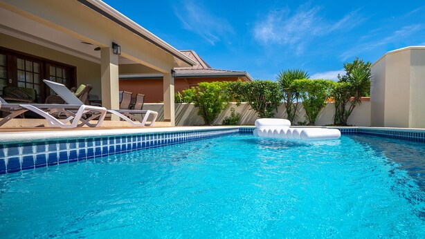 Una piscina con sillas de descanso y una zona cubierta.