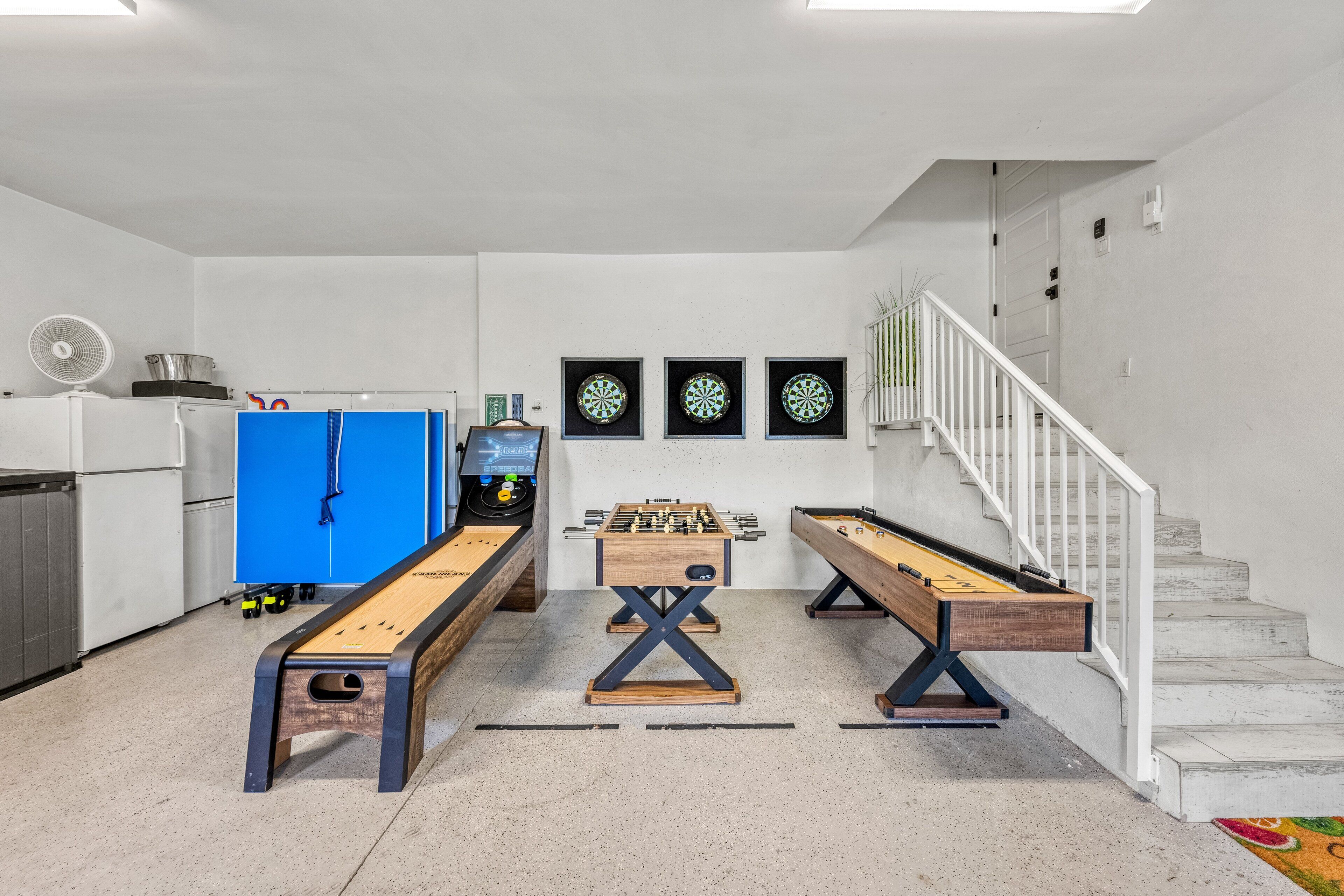 Una habitación con mesa de futbolín, dardos y un armario azul.