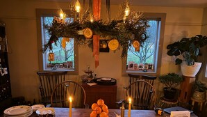 Una mesa de comedor dispuesta con diversos alimentos, velas y un adorno navideño.