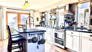 Una cocina moderna con una isla central, electrodomésticos de acero inoxidable y una variedad de utensilios y utensilios de cocina colgando en la pared.
