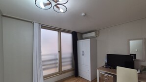 Ein kleiner, gut beleuchteter Raum mit Schreibtisch, Stuhl und großem Kleiderschrank.