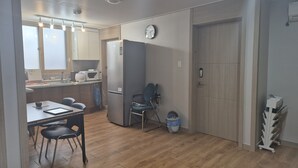 Eine kompakte Küche mit Kühlschrank, Mikrowelle und Spüle. Ein Essbereich mit Stühlen und Tisch ist vorhanden.