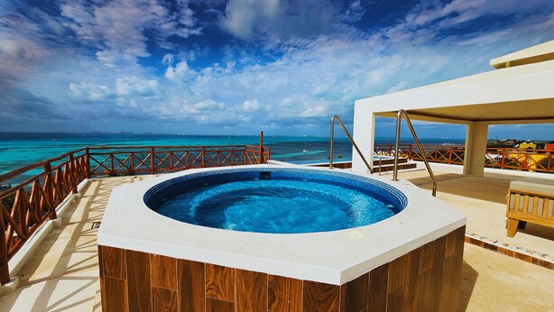 Un jacuzzi sur une terrasse offrant une vue sur l’océan et, au loin, sur les gratte-ciel de la ville.