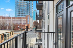 A modern building with a balcony, large windows, and a view of a city street.