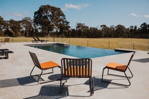 Una piscina al aire libre, sombrillas, sillones reclinables de piscina