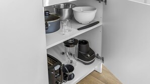 Eine Küche mit einem weißen Schrank, der verschiedene Küchenutensilien und Geräte beherbergt.