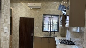 Eine moderne Küche mit Einbauherd, einem Fenster mit Gitterrost und einem dunklen Holzschrank.