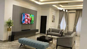 Ein modernes Wohnzimmer mit Fernseher, Sofa, Sitzbank und Couchtisch.