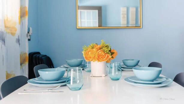 Ein Esstisch mit blauen Schüsseln, Tellern und einer Blumenvase.