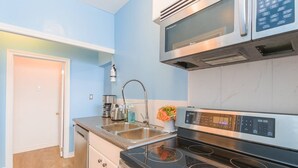Eine kompakte Küche mit einer Edelstahl-Mikrowelle, einem Backofen und einem Kochfeld.