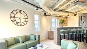 A modern living room with a green sofa, a marble coffee table, and a large wall clock.