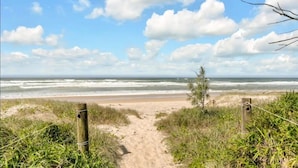 Ein Strandweg, der zum Meer führt, mit einem Holzzaun an beiden Seiten.