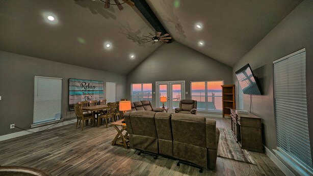 A spacious living area with a high ceiling, a dining table with chairs, a large couch, and a television mounted on the wall. -  Nocona Lakefront with 40 private acres, beds for 8, newly constructed in 2024! (Nocona)