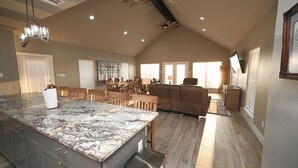 A spacious kitchen with a granite island, wooden chairs, and a dining area with a table and chairs. -  Nocona Lakefront with 40 private acres, beds for 8, newly constructed in 2024! (Nocona)