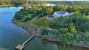 A house with a dock extending into a lake, surrounded by dense greenery. -  Nocona Lakefront with 40 private acres, beds for 8, newly constructed in 2024! (Nocona)