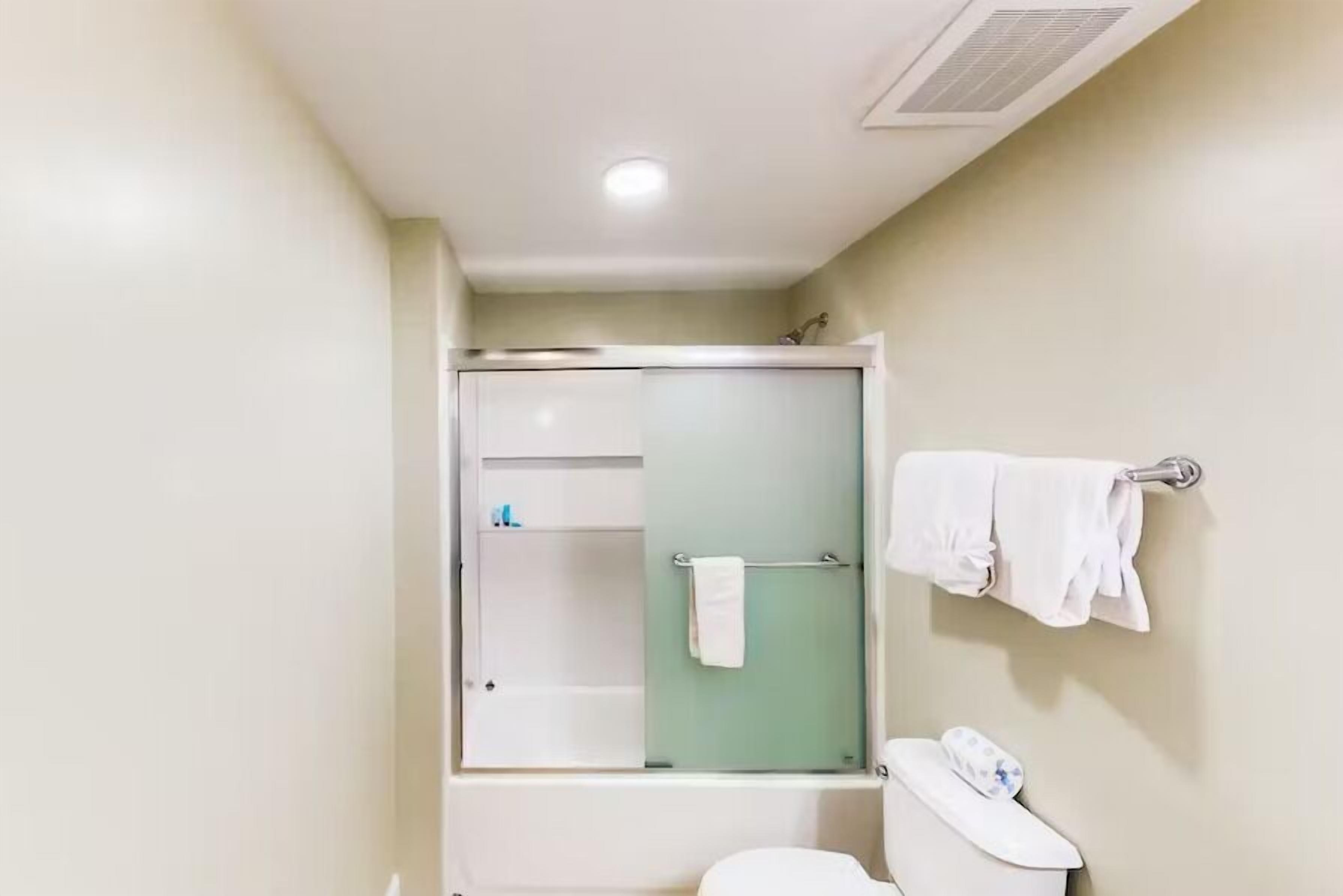 Un baño con ducha de vidrio, inodoro y barra para toallas.