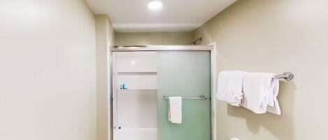 Un baño con ducha de vidrio, inodoro y barra para toallas.