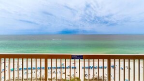 Blick auf einen Strand mit klarem Himmel und einem Schiffen am Horizont.