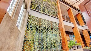 Un atrio de varios niveles con un muro de celosía, pilares de ladrillo y plantas en macetas.