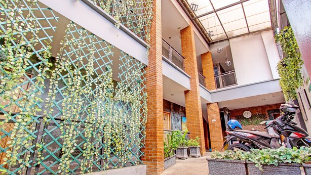 Un edificio de varios niveles con un espacio al aire libre cubierto, una motocicleta y plantas en macetas.