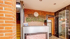 Una recepción con pared de ladrillo, un reloj, mostrador y vitrina de vidrio.