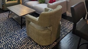 Un salon comprenant un canapé, un fauteuil, une table basse et un ventilateur de plafond. Il y a des fenêtres donnant sur un paysage enneigé.