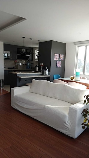 Una sala de estar moderna con sofá, mesa de comedor y área de cocina.