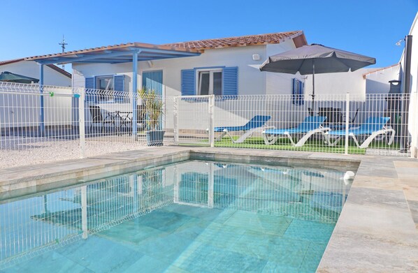 Relax by the serene pool surrounded by a garden and a Mediterranean-style house.